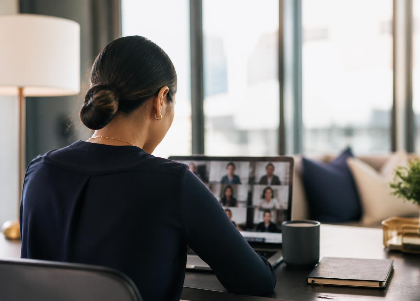 Filipino woman professional on a video call in a bright modern workspace, face not shown